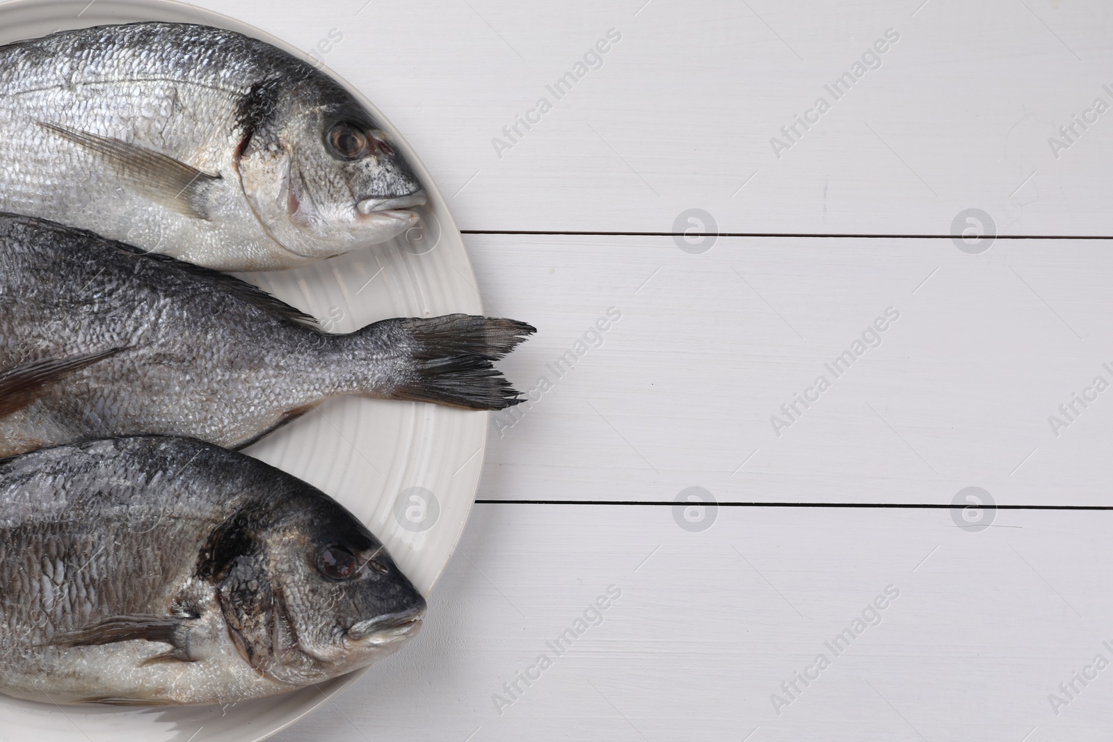 Photo of Fresh raw dorado fish on white wooden table, top view. Space for text