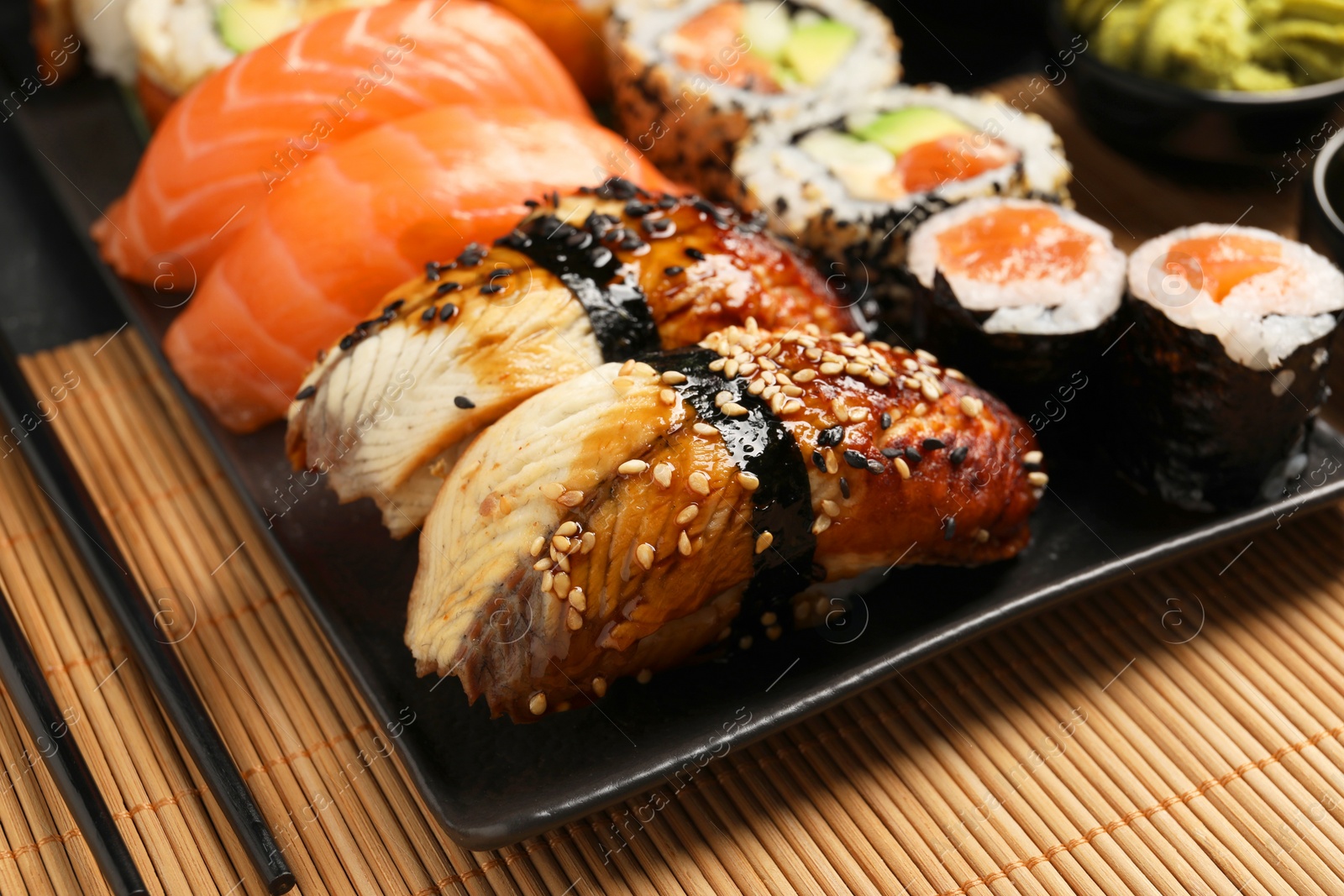 Photo of Set of delicious sushi rolls on mat, closeup