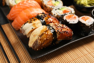 Photo of Set of delicious sushi rolls on mat, closeup