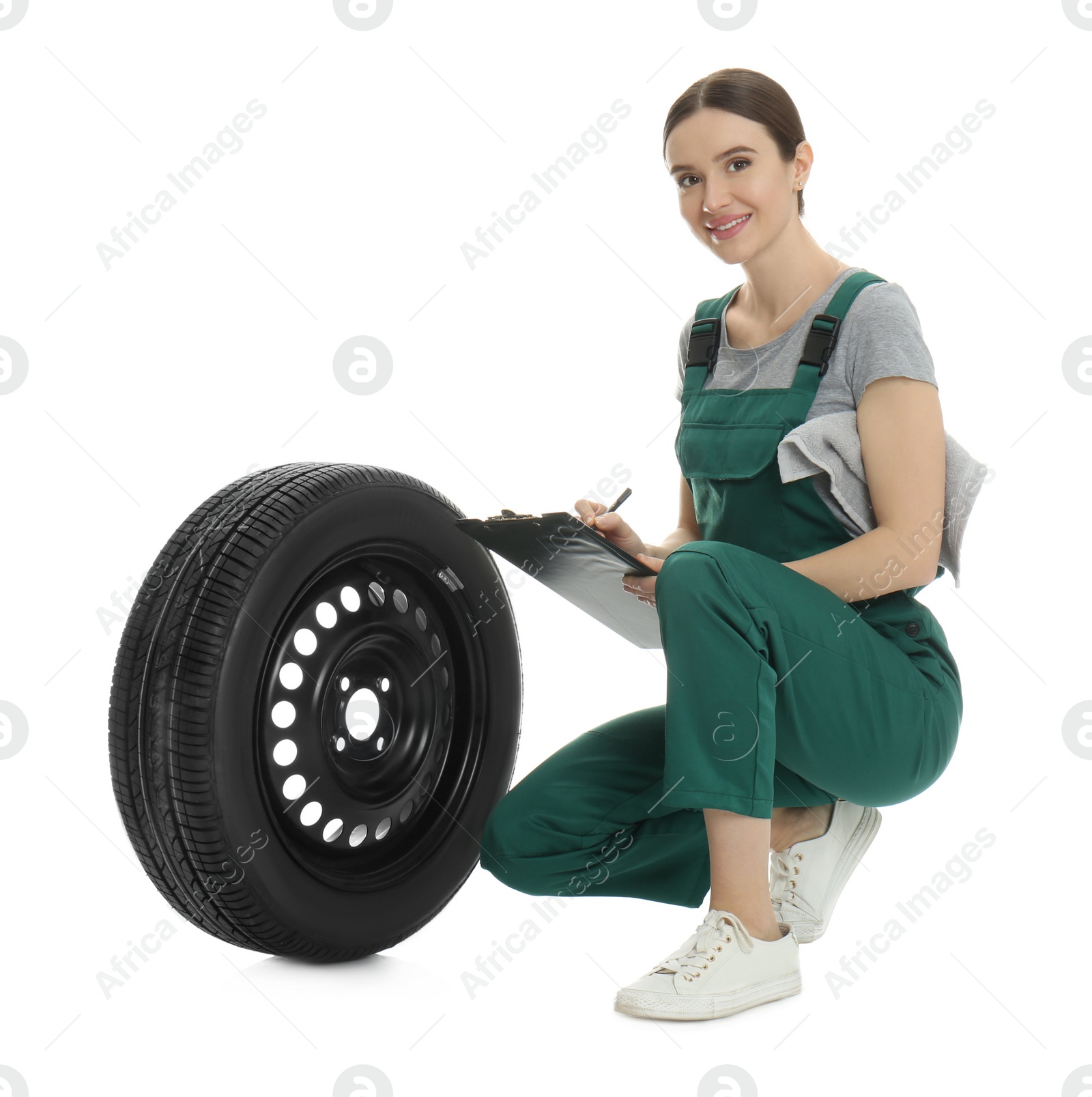 Photo of Professional auto mechanic with wheel and clipboard on white background