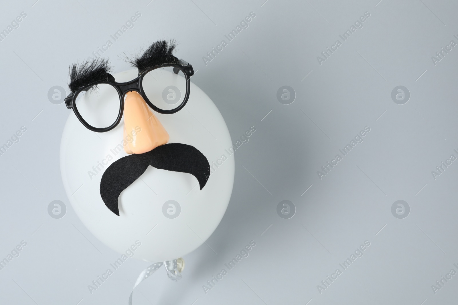 Photo of Man's face made of balloon, funny mask with fake mustache, nose and glasses on grey background, top view. Space for text