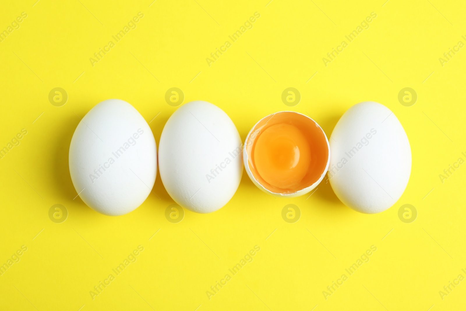 Photo of Fresh raw chicken eggs on yellow background, flat lay