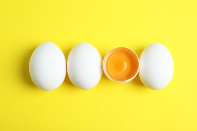 Fresh raw chicken eggs on yellow background, flat lay