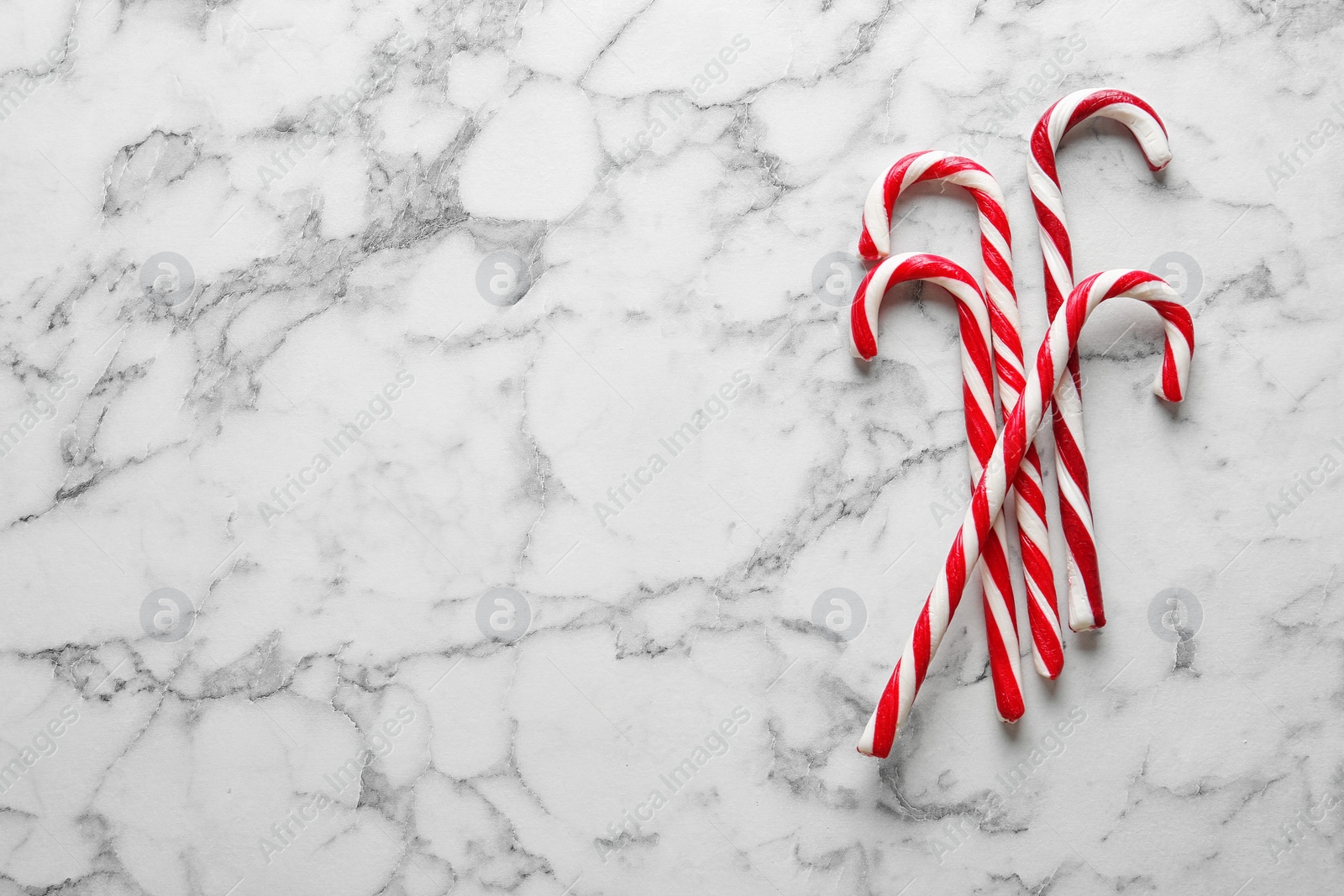 Photo of Candy canes on white marble background, flat lay with space for text. Traditional Christmas treat