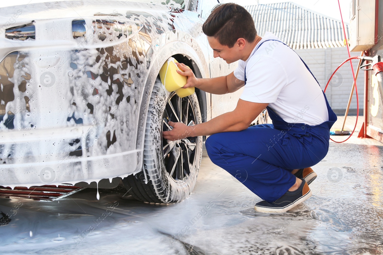 Photo of Worker cleaning automobile with sponge at car wash