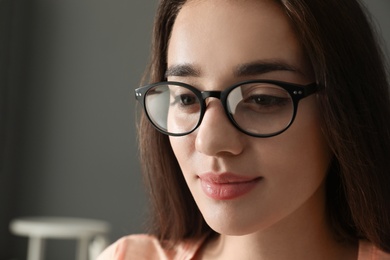 Photo of Beautiful young woman wearing glasses on blurred background. Ophthalmologist service