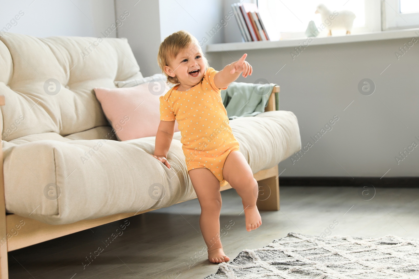 Photo of Cute baby learning to walk in living room