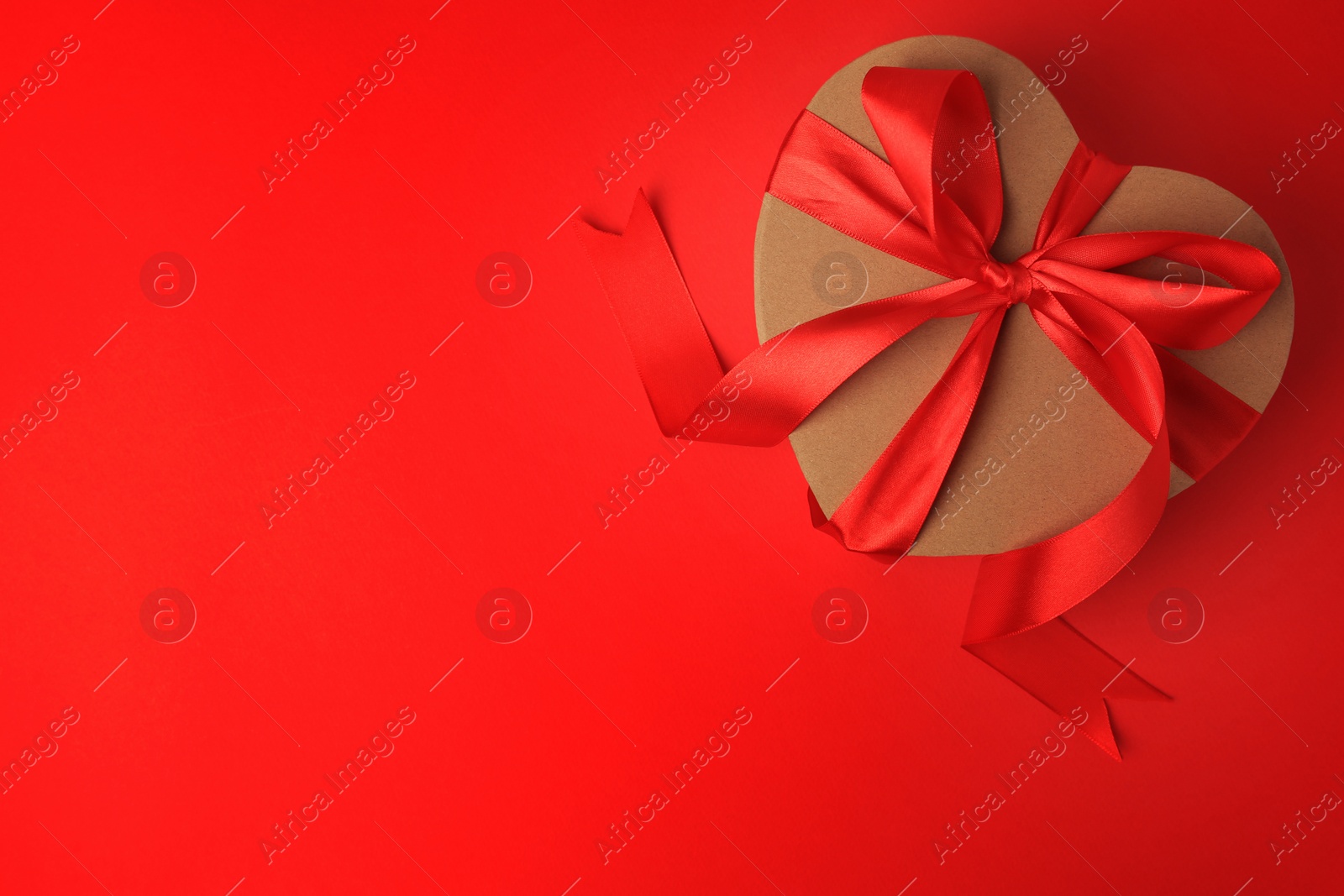 Photo of Beautiful heart shaped gift box with bow on red background, top view. Space for text