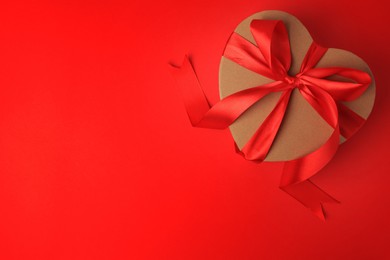 Photo of Beautiful heart shaped gift box with bow on red background, top view. Space for text