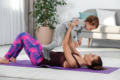 Woman doing fitness exercises together with son at home