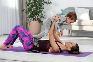 Photo of Woman doing fitness exercises together with son at home