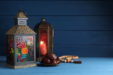Photo of Arabic lanterns, dates and misbaha on wooden table. Space for text