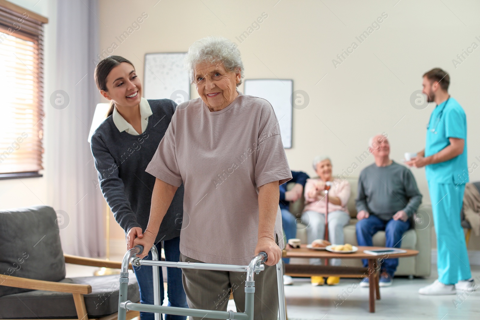 Photo of Care worker helping to elderly woman with walker in geriatric hospice