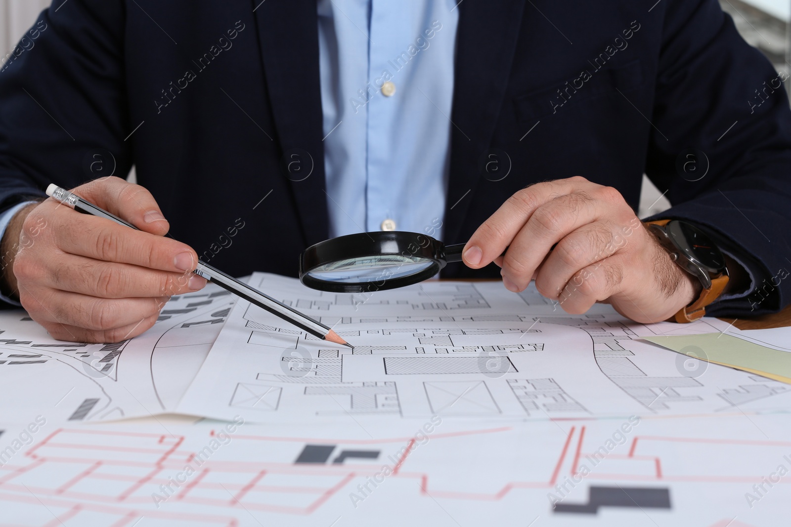 Photo of Professional cartographer working with cadastral map at table, closeup