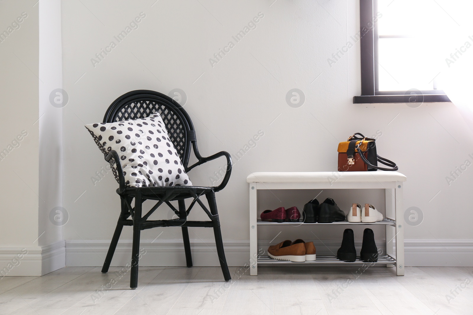 Photo of Collection of stylish shoes on rack storage near white wall in room