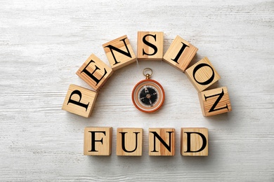 Photo of Flat lay composition with words PENSION FUND and compass on wooden background