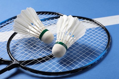 Feather badminton shuttlecocks and rackets on blue background, closeup
