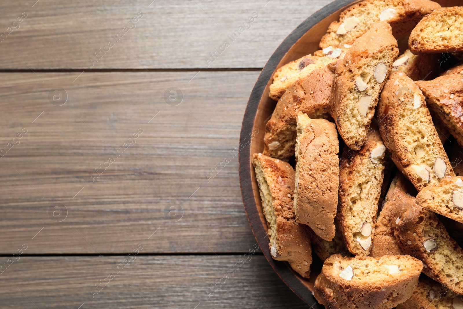 Photo of Traditional Italian almond biscuits (Cantucci) on wooden table, top view. Space for text