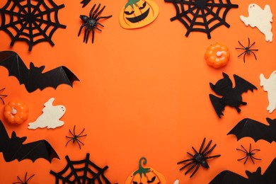 Photo of Flat lay composition with bats, pumpkins, ghosts and spiders on orange background, space for text. Halloween celebration