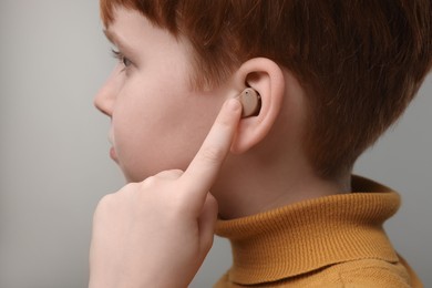 Photo of Little boy with hearing aid on grey background, closeup