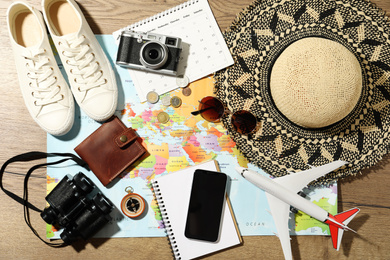 World map and items on wooden background, flat lay. Travel during summer vacation