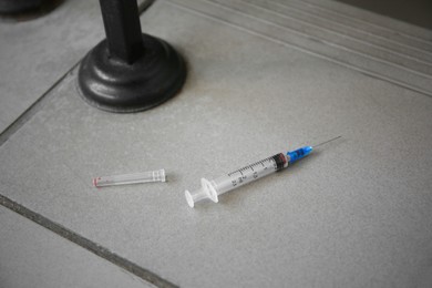 Photo of Disposable syringe with needle on tiled surface