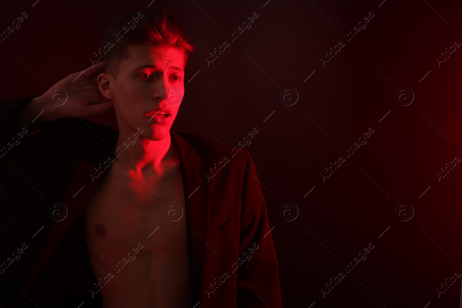 Photo of Sexy young man on dark background in neon light. Space for text