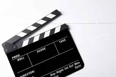 Photo of Clapperboard on white wooden table, top view. Space for text