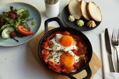 Photo of Tasty Shakshouka served on white marble table, above view