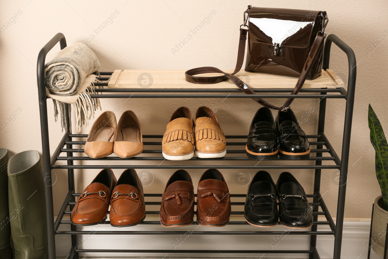 Photo of Rack with different shoes near beige wall in room