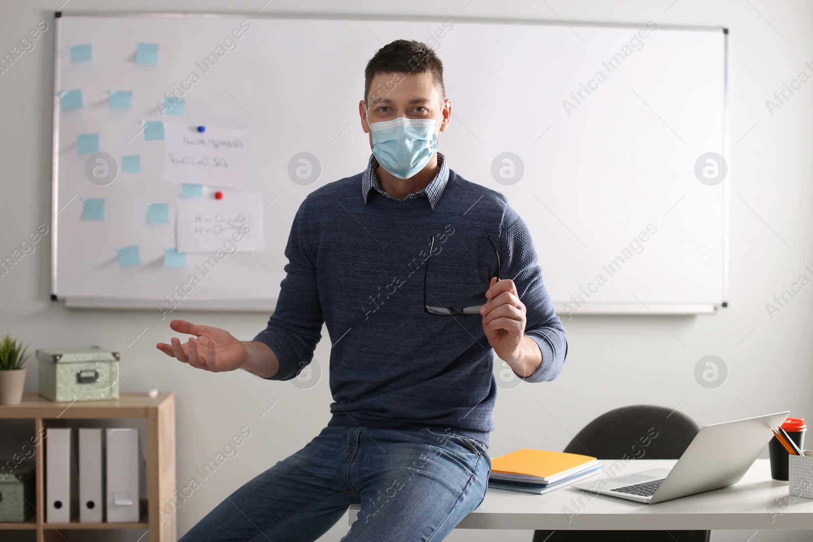 Photo of Teacher with protective mask conducting lesson in classroom. Reopening after Covid-19 quarantine