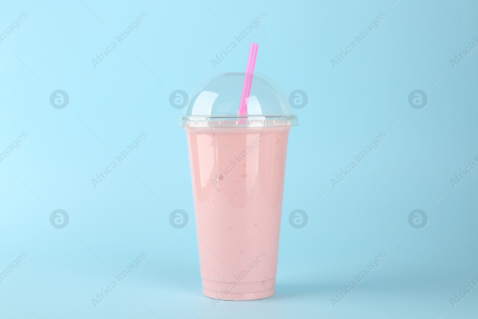 Photo of Plastic cup of tasty smoothie on light blue background