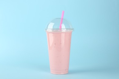 Plastic cup of tasty smoothie on light blue background