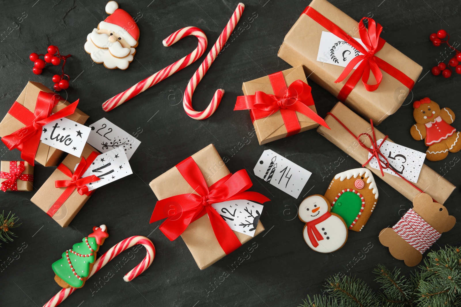 Photo of Flat lay composition with gift boxes and Christmas treats on black table. Creating advent calendar