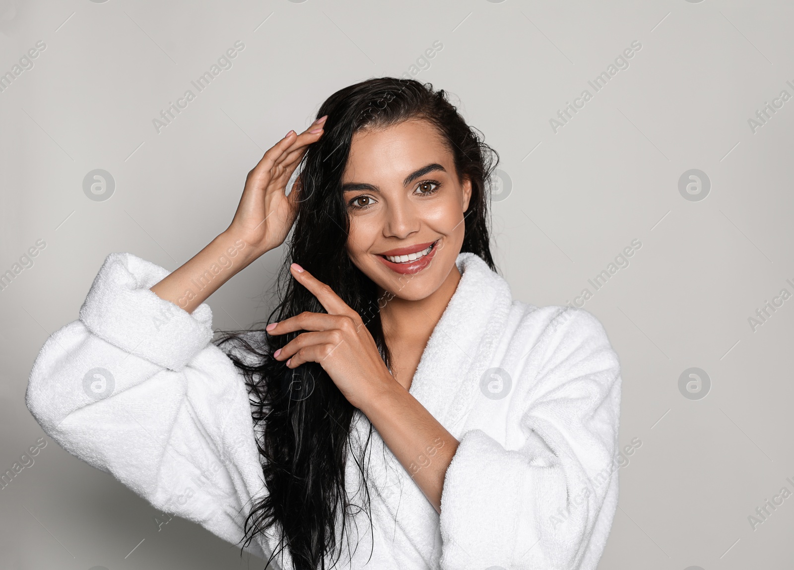 Photo of Beautiful young woman wearing bathrobe on light background