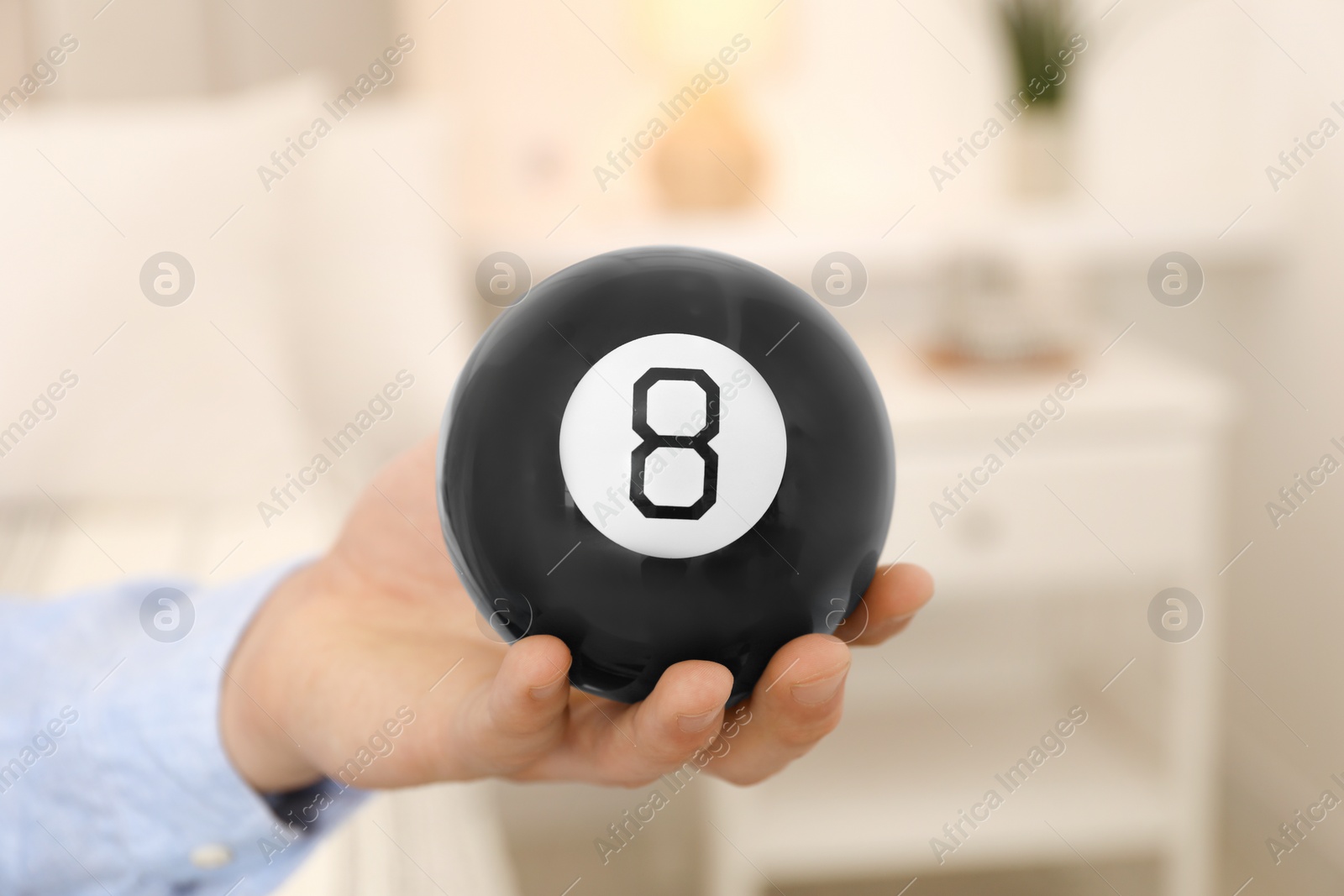 Photo of Man holding magic eight ball indoors, closeup