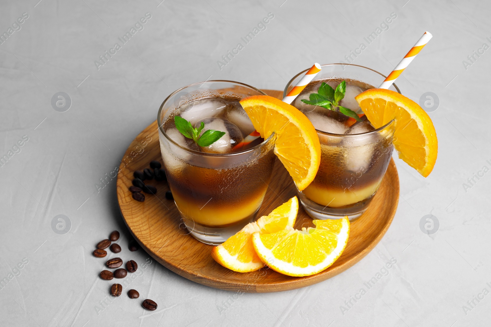 Photo of Tasty refreshing drink with coffee and orange juice on grey table