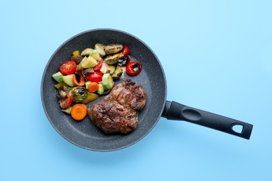 Tasty fried steak with vegetables in pan on turquoise background, top view