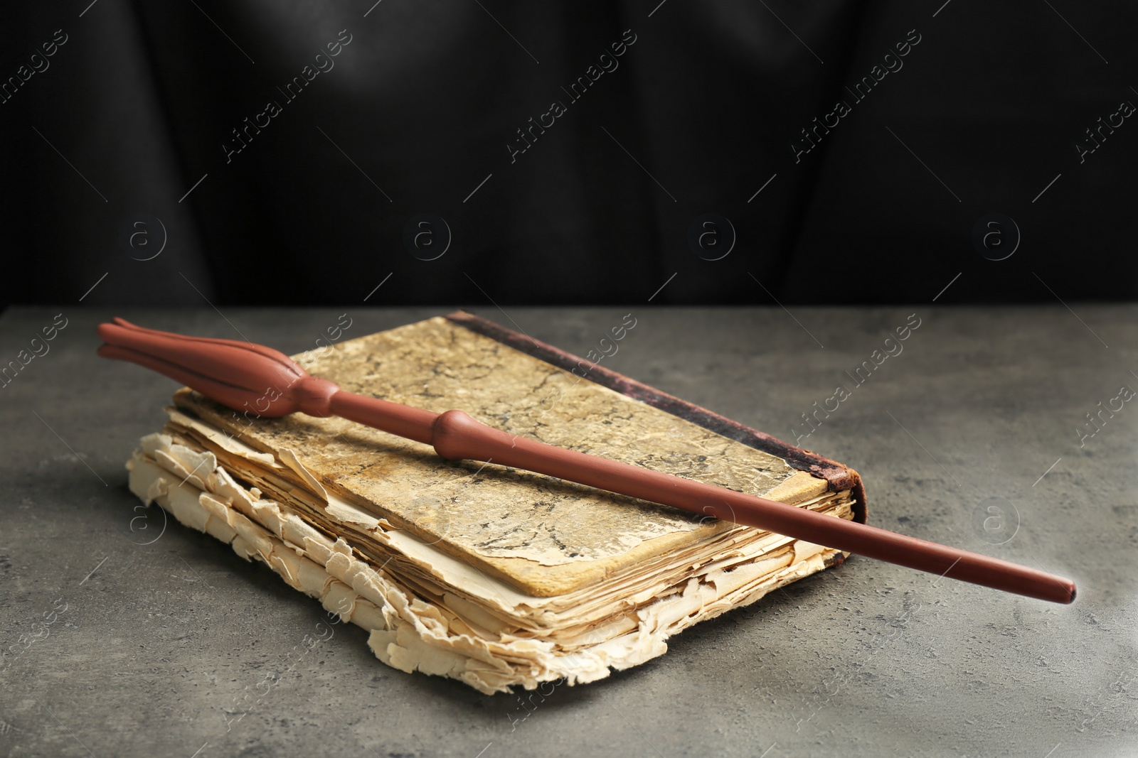 Photo of Magic wand and old book on light grey table