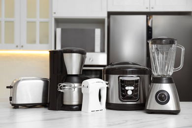 Photo of Set of modern home appliances on white marble table in kitchen