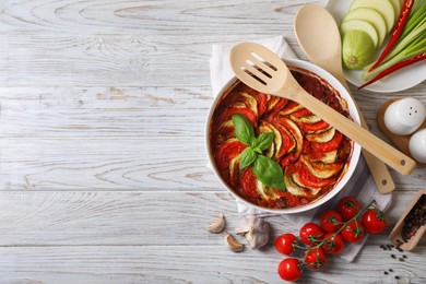 Delicious ratatouille and ingredients on white wooden table, flat lay. Space for text