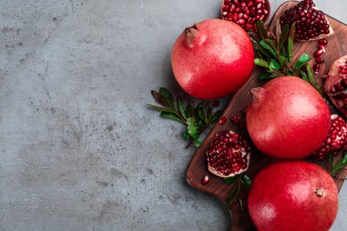 Photo of Delicious ripe pomegranates on grey table, flat lay. Space for text