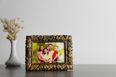 Photo of Vintage square frame with family photo and vase of dry flowers on wooden table, space for text