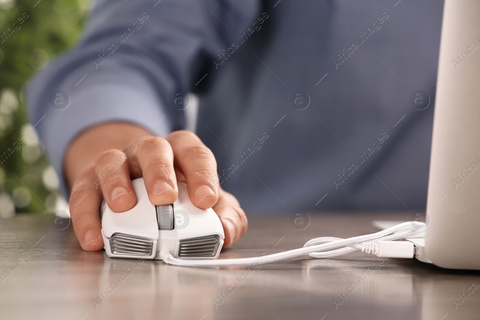 Photo of Man using computer mouse with laptop at table, closeup