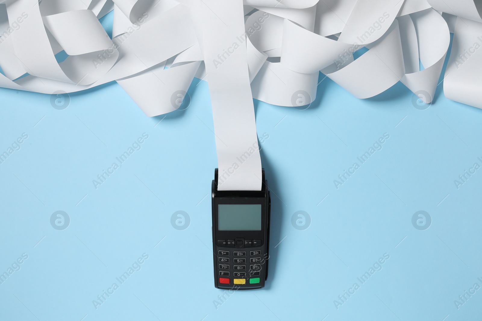 Photo of Payment terminal with thermal paper for receipt on light blue background, top view