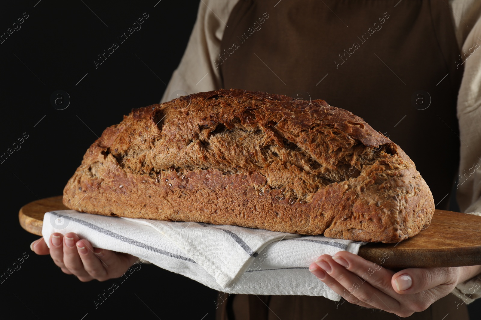 Photo of Woman holding freshly baked bread on black background, closeup