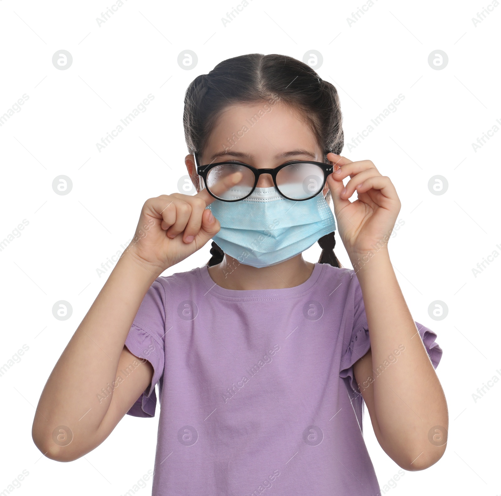 Photo of Little girl wiping foggy glasses caused by wearing medical face mask on white background. Protective measure during coronavirus pandemic