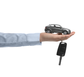 Man holding key and miniature automobile model on white background, closeup. Car buying