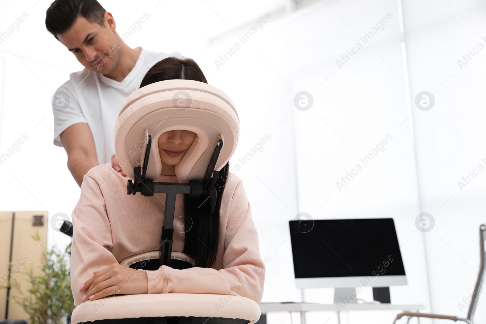 Photo of Woman receiving massage in modern chair indoors