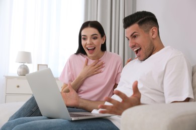 Photo of Emotional couple participating in online auction using laptop at home